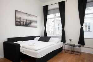 Une chambre moderne avec un grand lit, une petite table de chevet et une fenĂȘtre avec des rideaux.