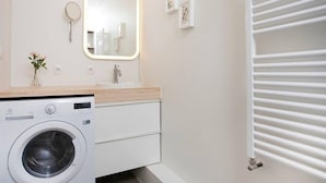 A modern bathroom with a washing machine, a mirror with a light, and a radiator. - Stunning 2BR apt with balcony view in Reykjavik (Reykjavík)