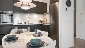 Una cocina moderna con comedor, electrodomésticos de acero inoxidable y un reloj en la pared.