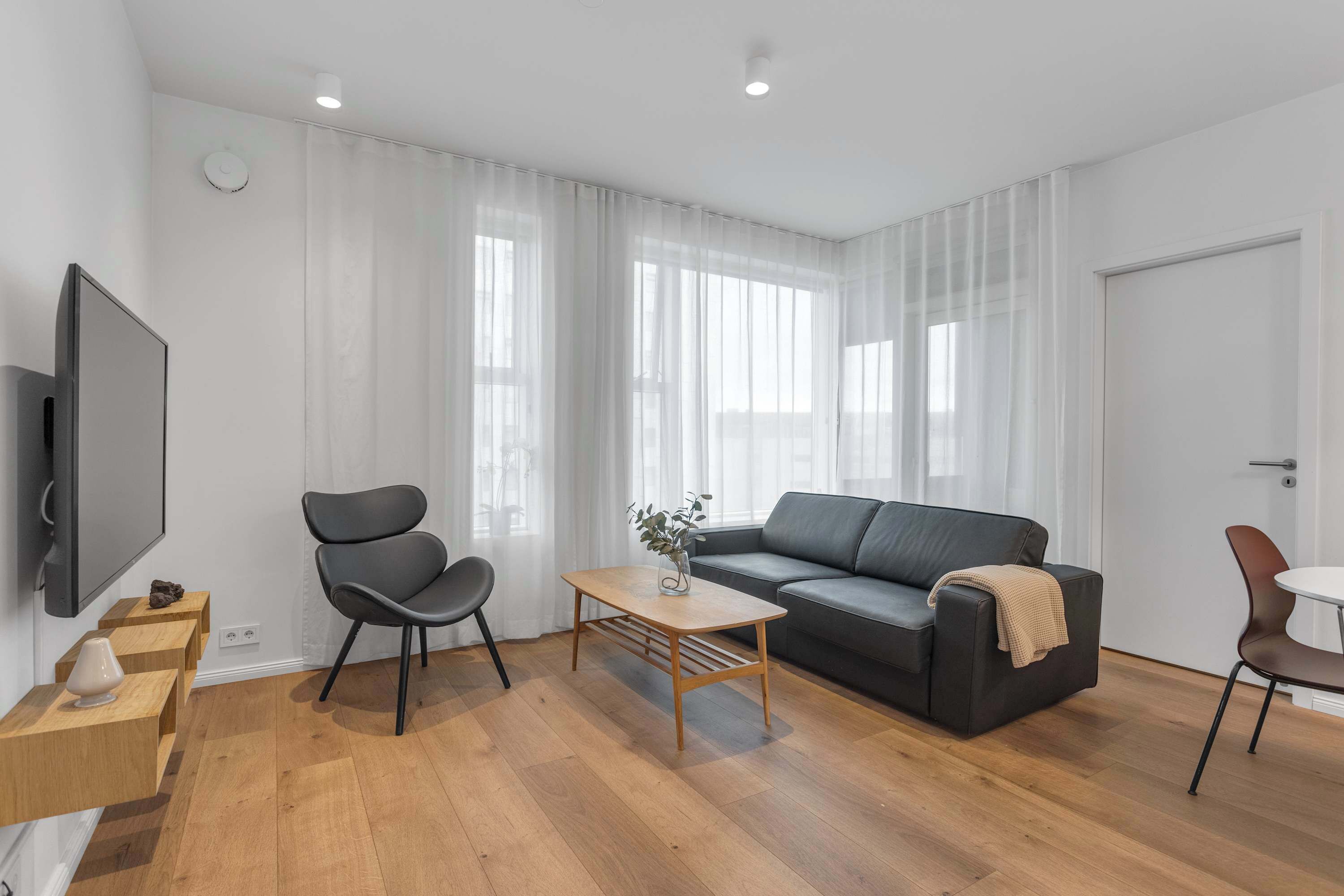 Una sala de estar moderna con un sofá, una mesa de centro y un televisor montado en la pared.