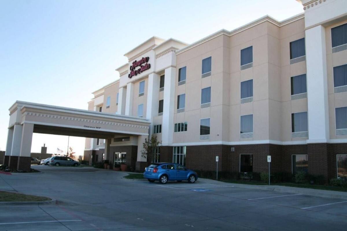 Un hotel Hampton Inn amb entrada coberta, diversos pisos i un pàrquing.