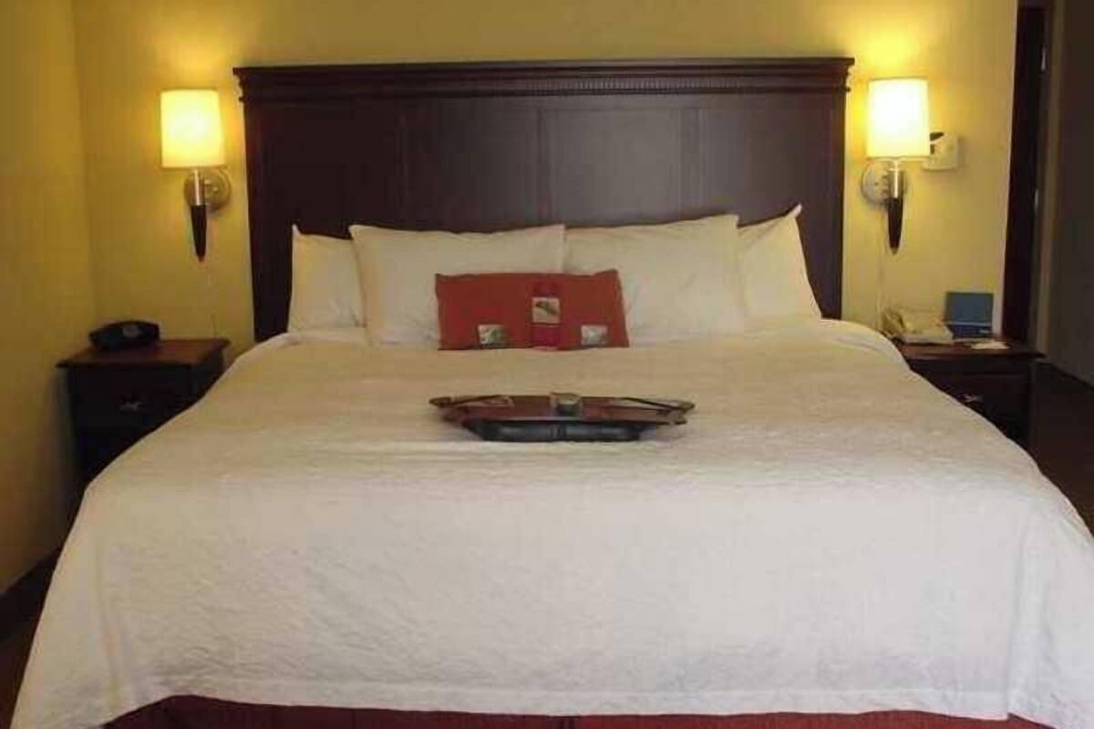 Habitació d'hotel amb un llit gran, dues taules de nit i dues làmpades penjades a la paret.