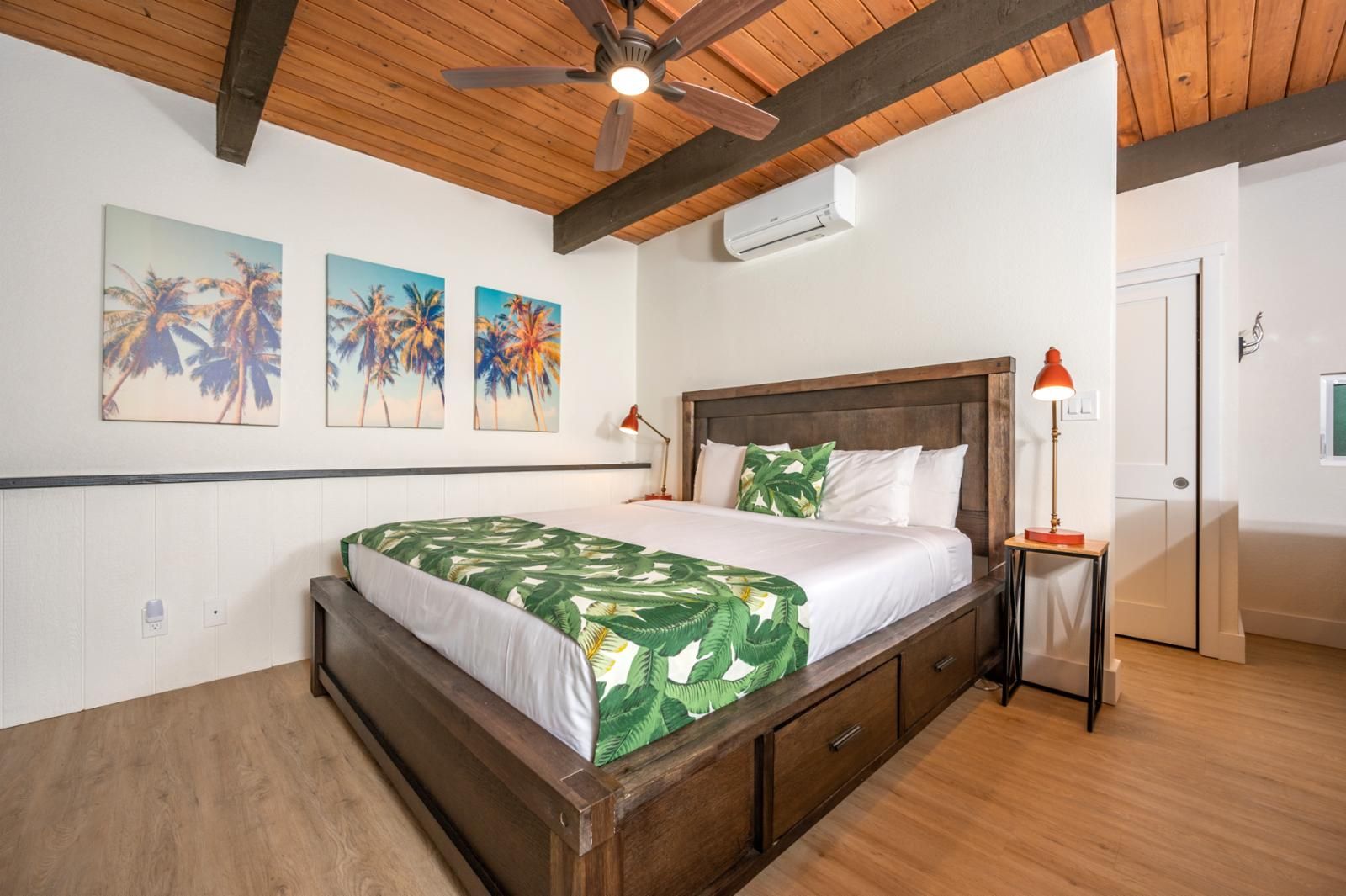 A bedroom with a wooden bed, a ceiling fan, and wall-mounted air conditioning.