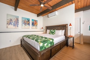 Une chambre avec un lit en bois, un ventilateur de plafond et un climatiseur fixé au mur.