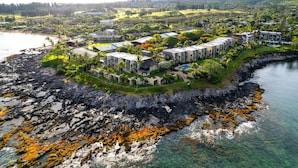 Eine Luftaufnahme eines Küstenresorts mit mehreren Gebäuden, einer felsigen Küstenlinie und klarem Wasser.