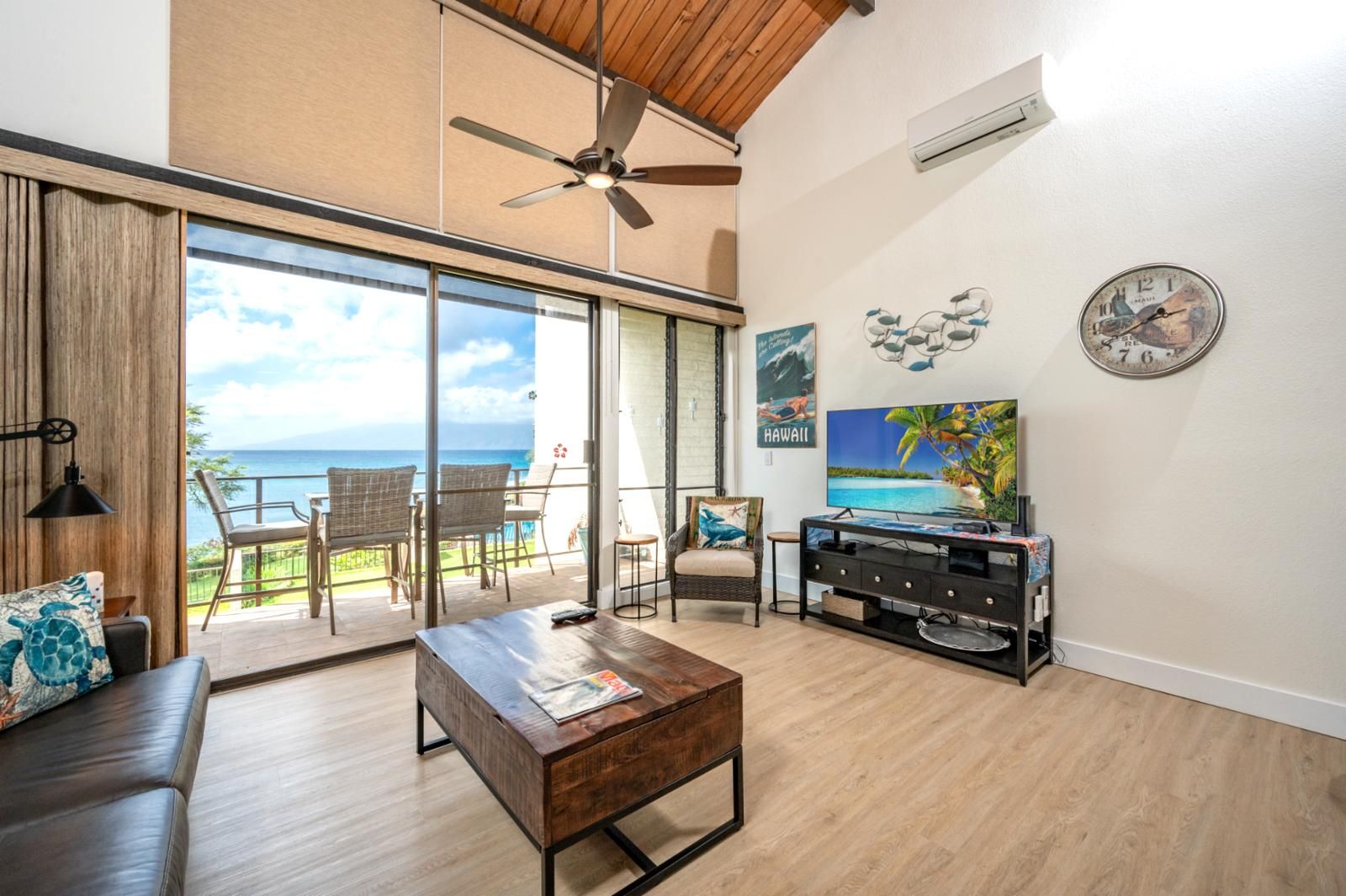 A spacious living area with a large sliding glass door leading to a balcony with a view of the ocean.
