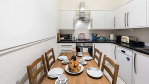 A compact kitchen with white cabinets, a microwave, a toaster, and a coffee maker. - Ealing garden flat by Walpole Park (London)