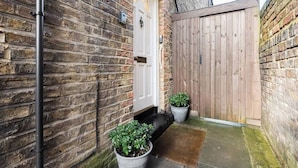 A brick wall, a wooden gate, and a white door. - Ealing garden flat by Walpole Park (London)