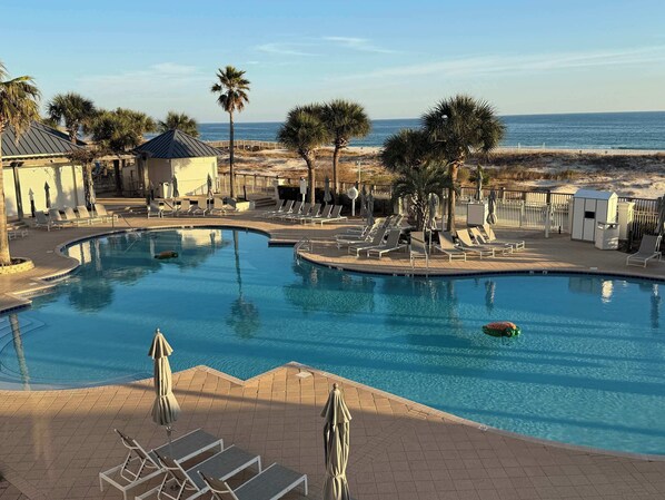 Relax by the serene pool surrounded by lounge chairs and umbrellas, with a tranquil ocean view.