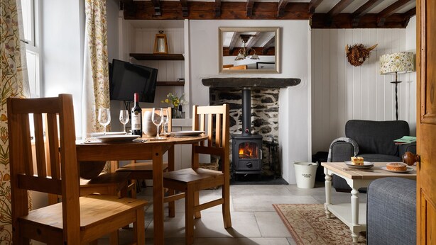 A cozy living room with a stone fireplace, wooden furniture, and a television.