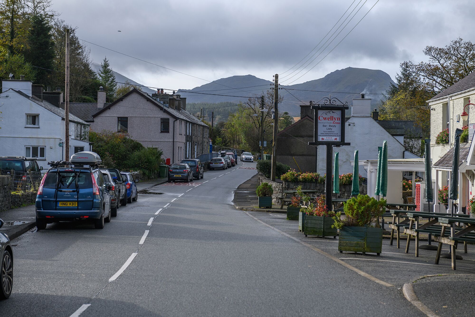 A street view with parked cars, a sign for 'Cwellyn Arms Bar & Bistro', and a mountain in the background.