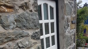 A stone building with a white door and a black handle.