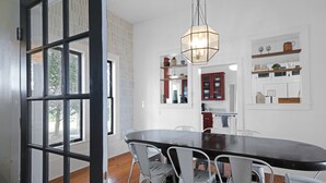 A dining area with a large table, white chairs, and a hanging light fixture. - Country Farmhouse close to Texas A&M, wedding venues, & wineries! (Navasota)
