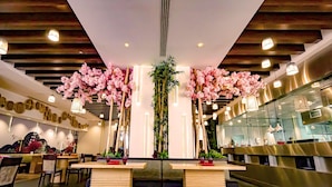 En restaurantindretning med trælofter, kaskader af lyserøde blomster og moderne belysning.