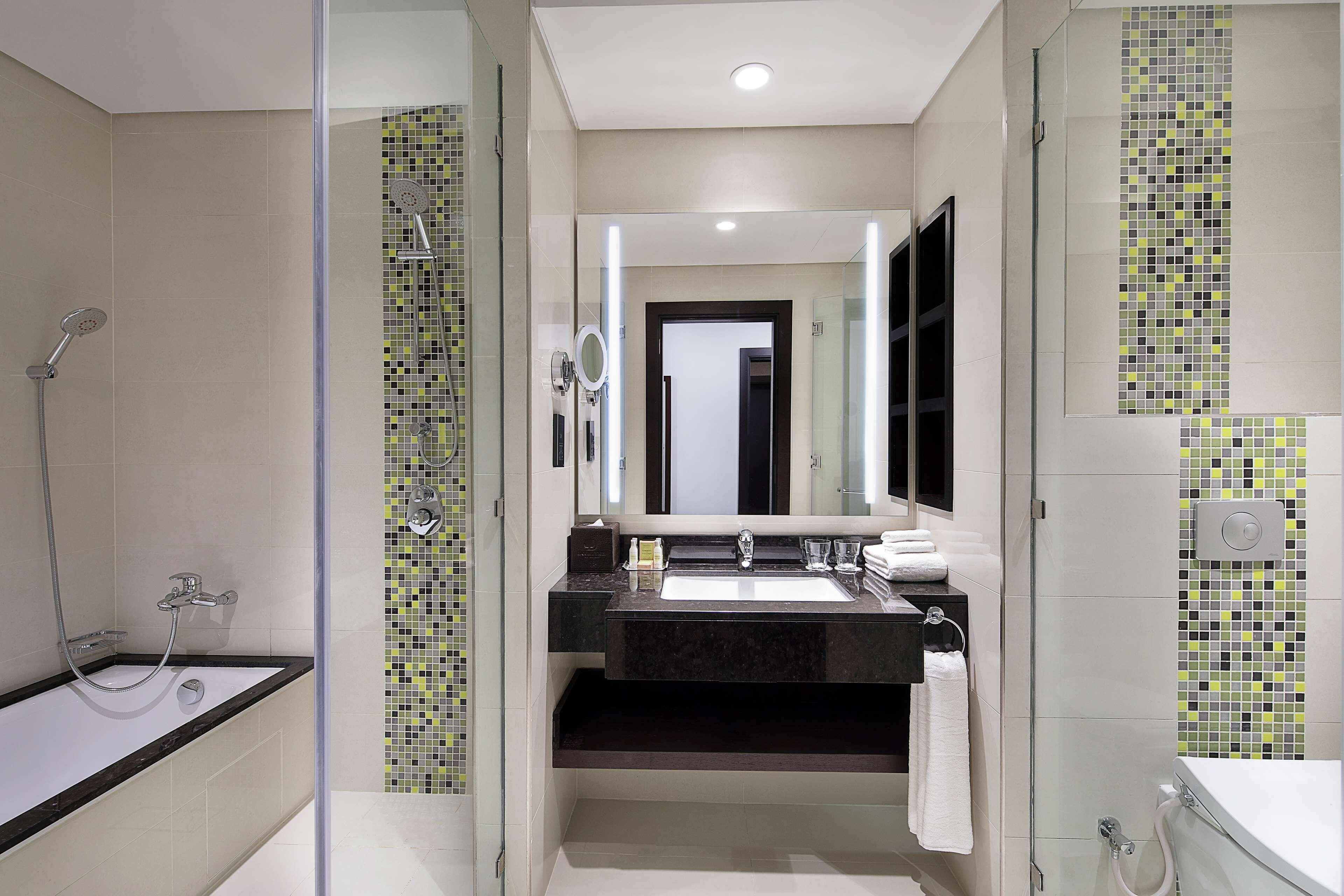 A modern bathroom with a glass-enclosed shower, a large mirror, and a black countertop sink.
