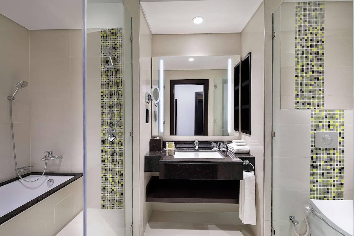 A modern bathroom with a glass-enclosed shower, a large mirror, and a black countertop sink.