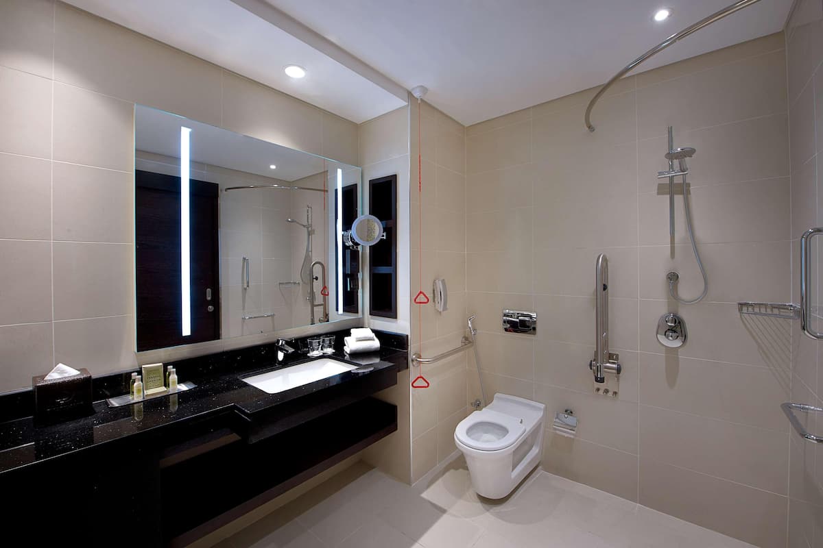 A modern bathroom with a black countertop, a white toilet, and a shower area.