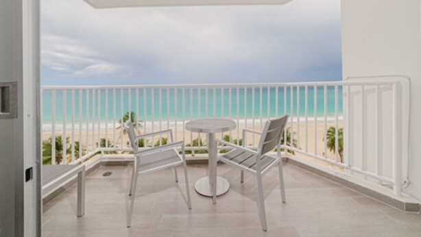 A balcony with a white railing, a round table, and two chairs. - Oceanfront Luxury Escape  (Carolina)