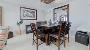A dining area with a wooden table, six chairs, a vase with flowers, and a framed picture on the wall. - Oceanfront Luxury Escape  (Carolina)