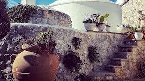 Un bâtiment blanc surmonté d’un dôme, avec des marches en pierre et des plantes en pot.