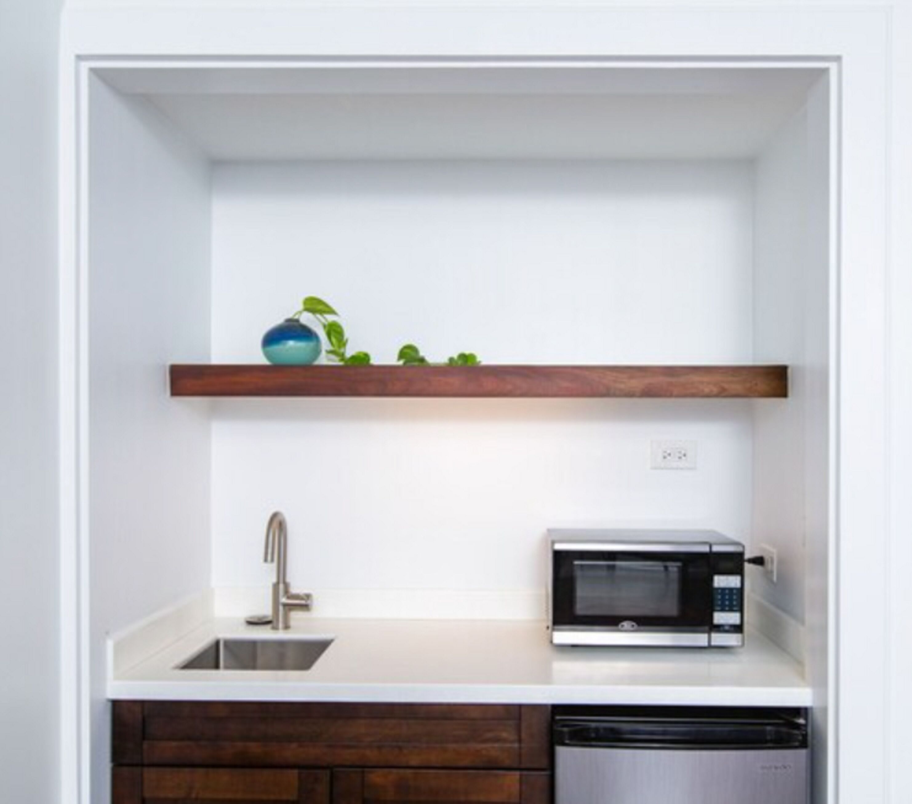 A compact kitchen with a white countertop, a built-in sink, a microwave, and a dishwasher.