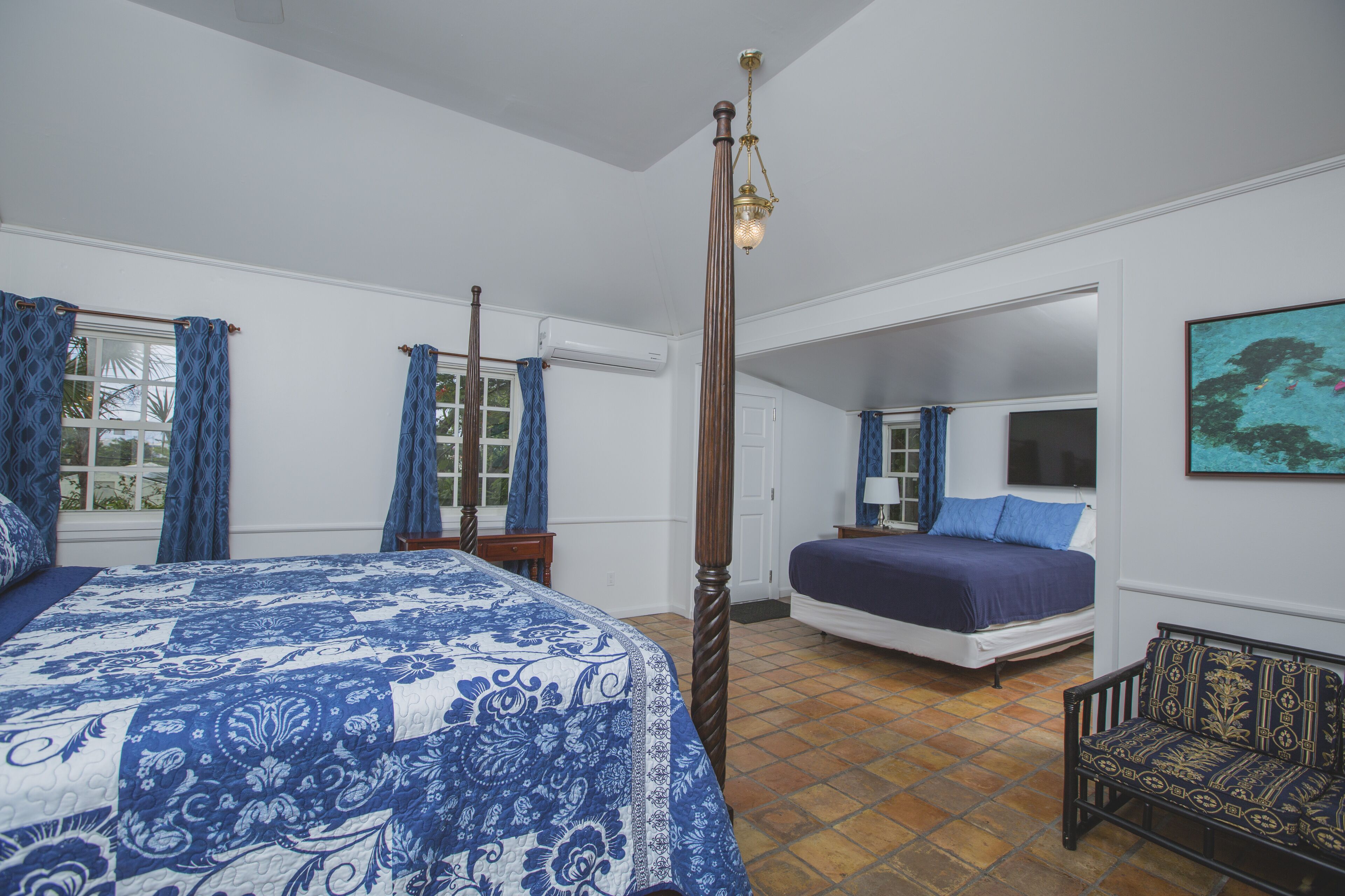 A bedroom with a four-poster bed, a nightstand, a chair, and a painting on the wall.