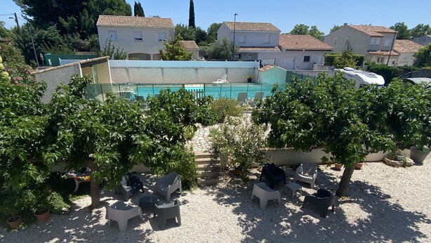 A residential area with a swimming pool, outdoor seating, and potted plants.