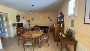 A dining area with a wooden table and chairs, a fireplace, and a kitchen area with a cabinet and a window.