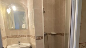 Une salle de bain avec un lavabo, un miroir et une douche.