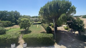 A garden with a swing set, neatly trimmed hedges, and a large tree.