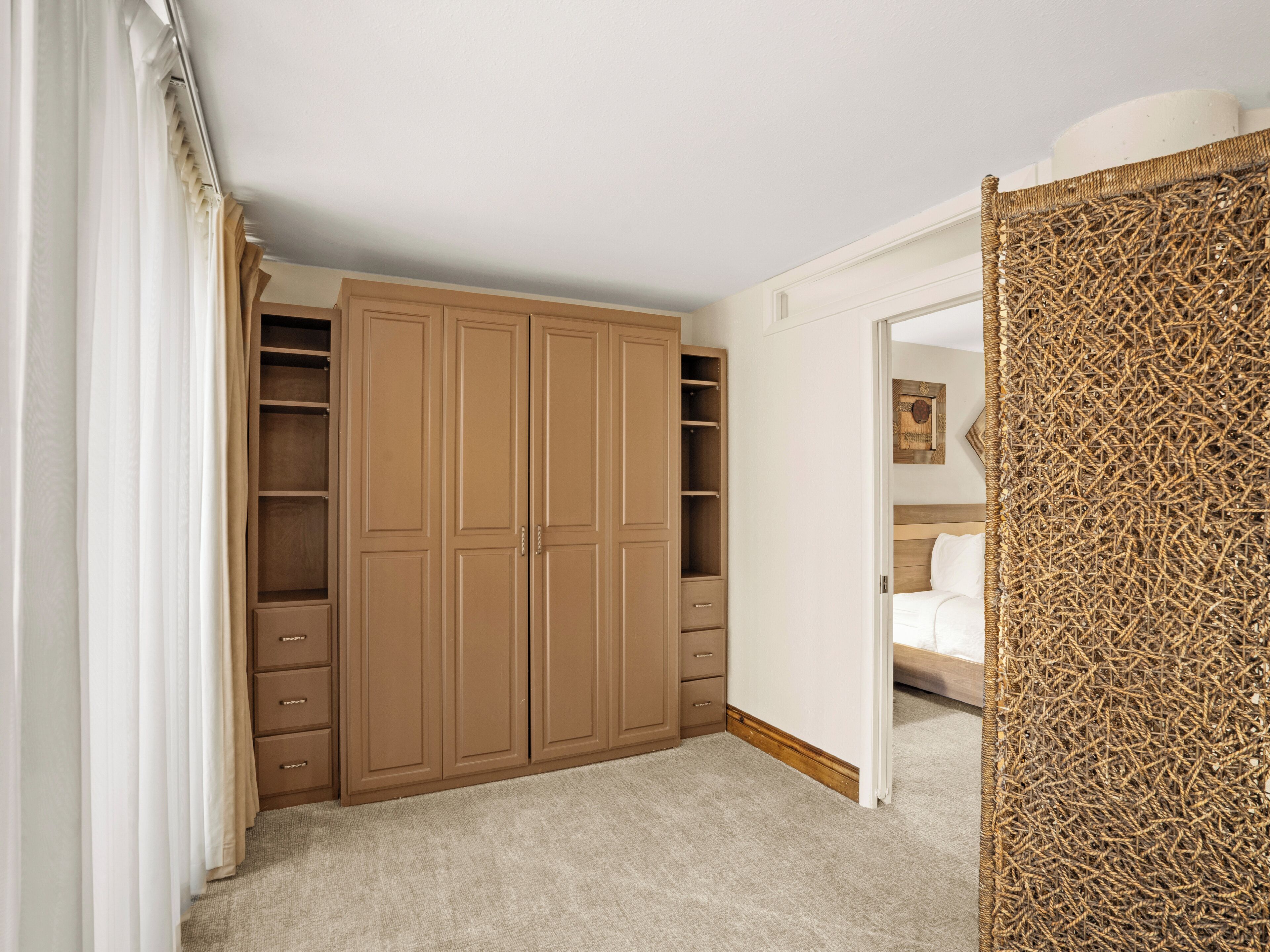 A bedroom with a large wardrobe, a bed with a wooden headboard, and a textured wall panel.