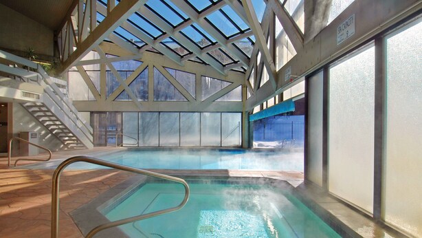 An indoor swimming pool with a skylight, stairs, and a capacity sign.