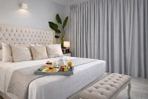 A neatly made bed with a tray of breakfast, a bedside lamp, and a large window with curtains. - Villa Almihauss Adults-Only  (Afantou)