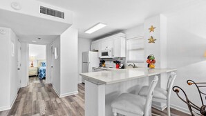 A modern kitchen with white cabinets, a central island, and bar stools.
