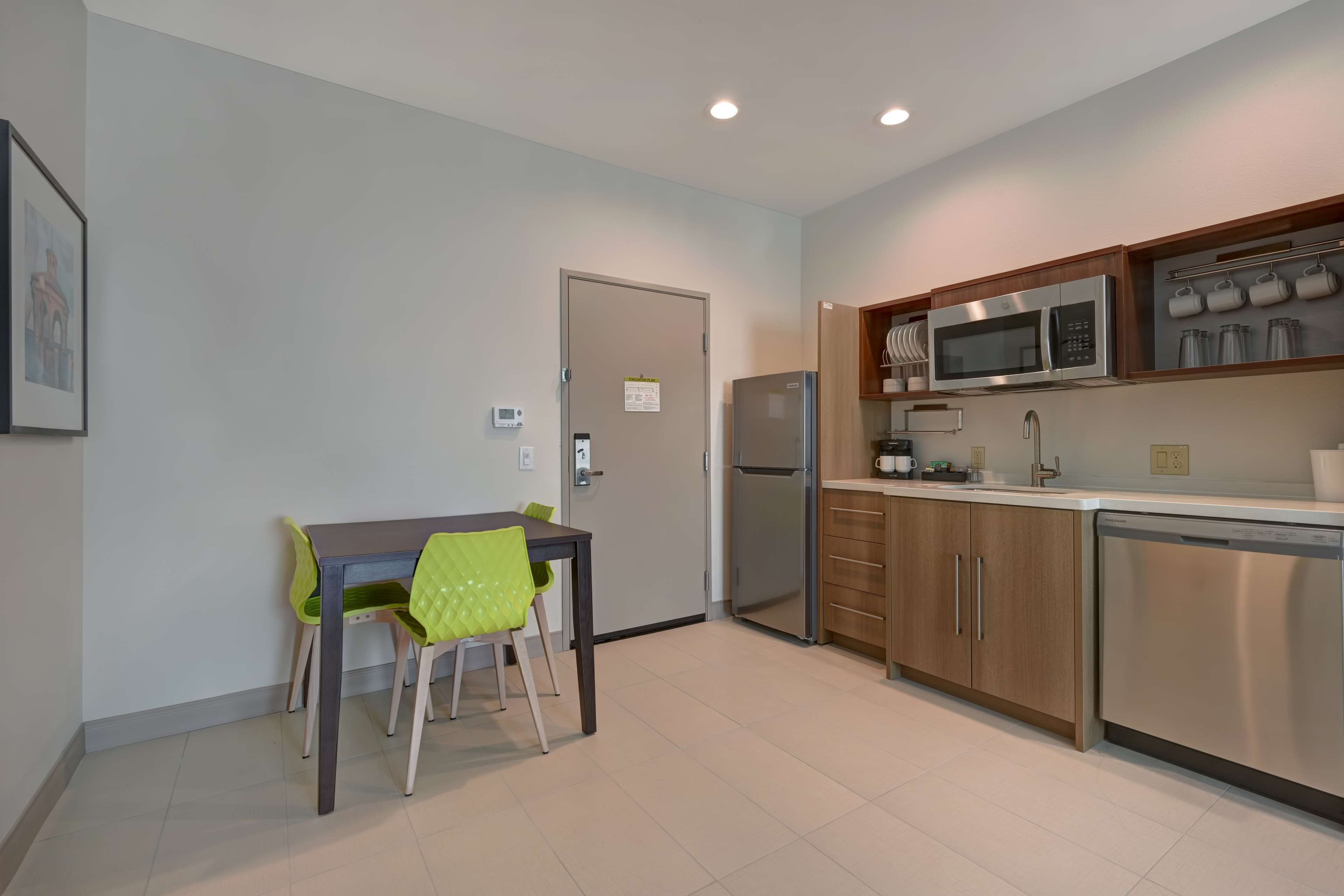 A modern kitchen with stainless steel appliances, wooden cabinets, and a dining area with a table and chairs.
