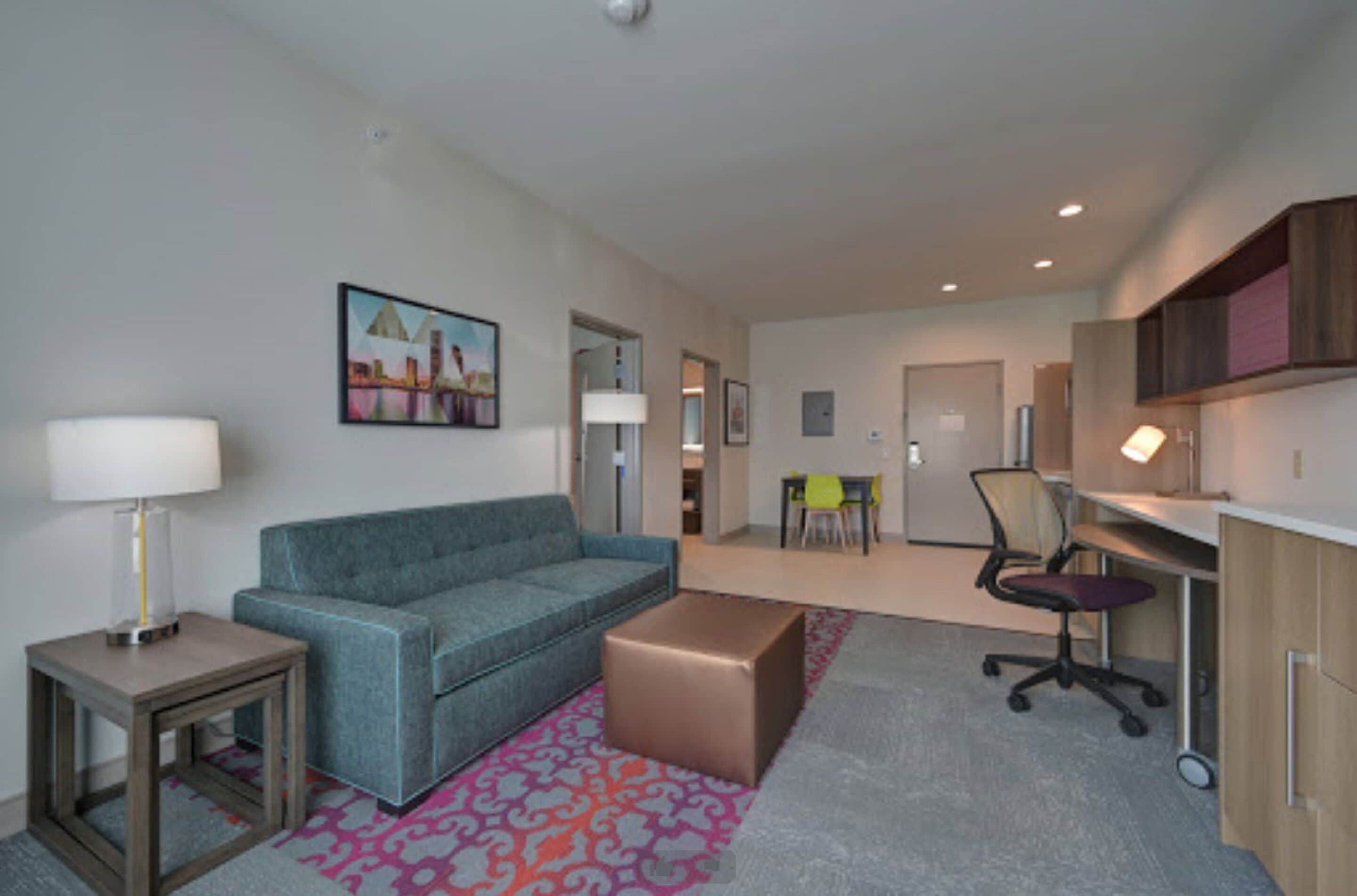 A modern living room with a sofa, a coffee table, a lamp, and a painting on the wall.