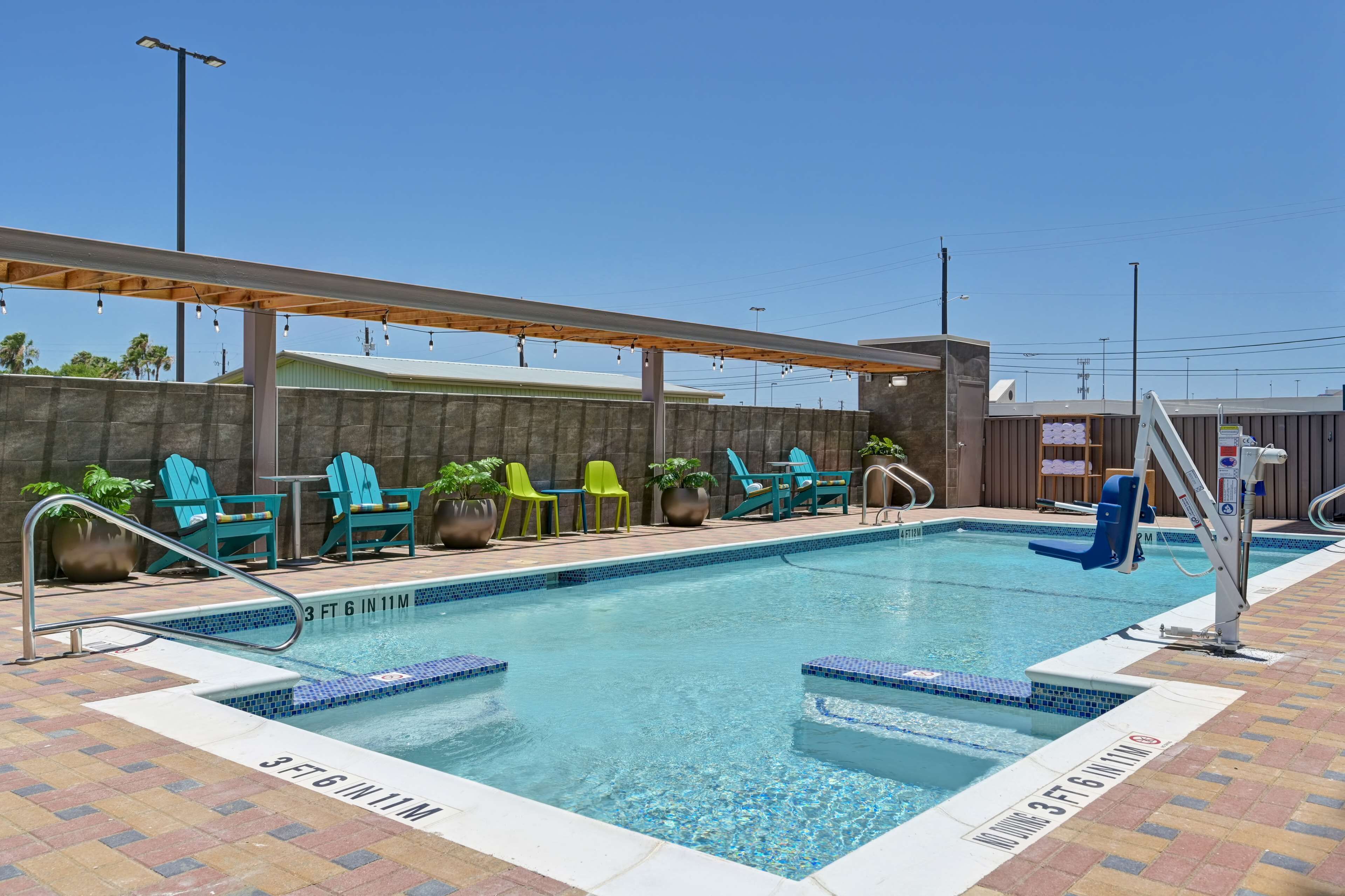 A pool area with a clear blue pool, a wooden deck, and several chairs.