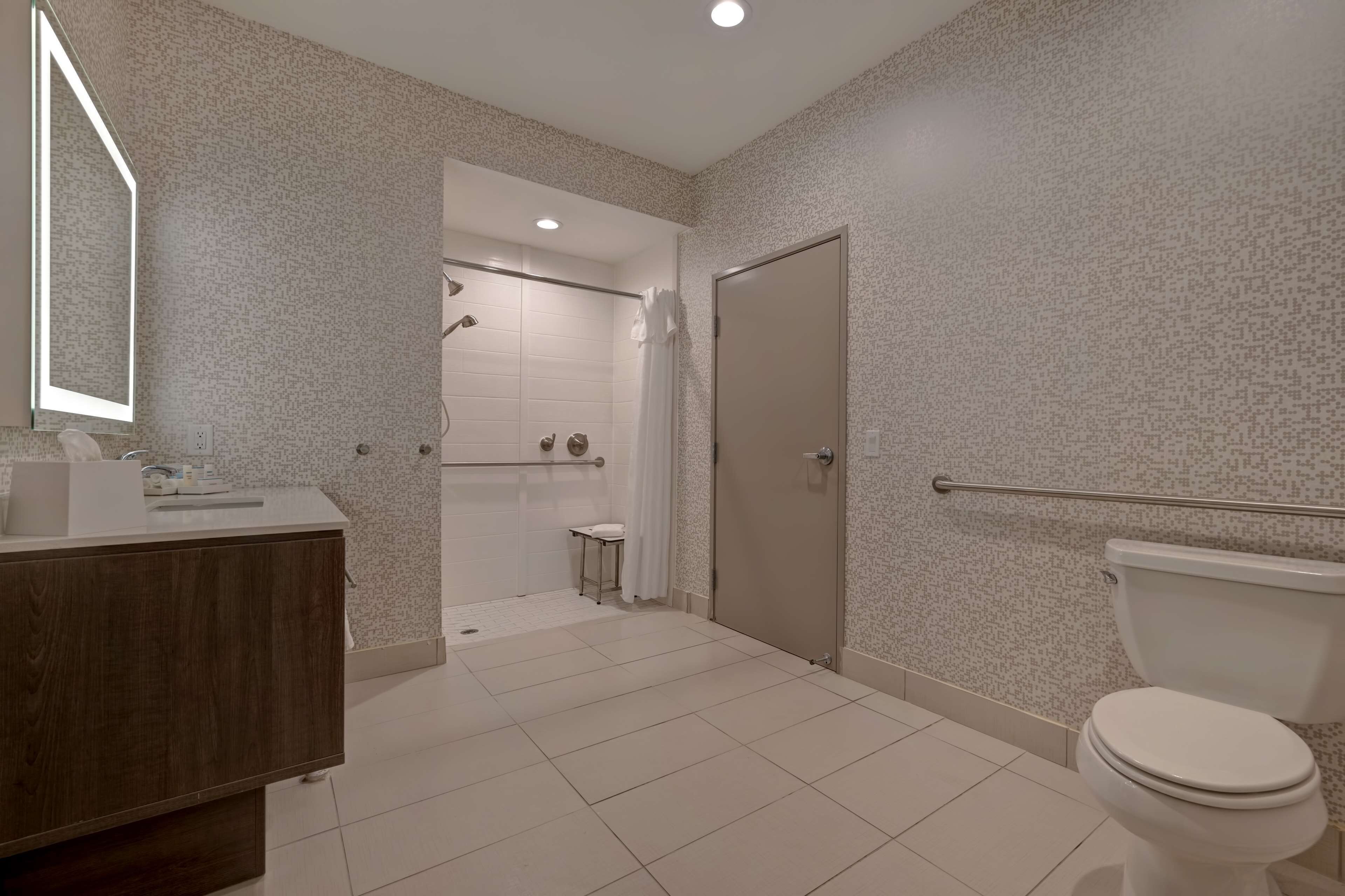 Une salle de bain moderne équipée d’une douche, de toilettes et d’un meuble-lavabo.