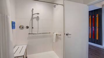 A modern shower with a glass door, a towel rack, and a small white table.