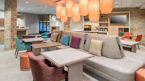 Ein stilvoller Lounge-Bereich mit einer Couch, Sesseln, Tischen und hängenden Pendelleuchten.