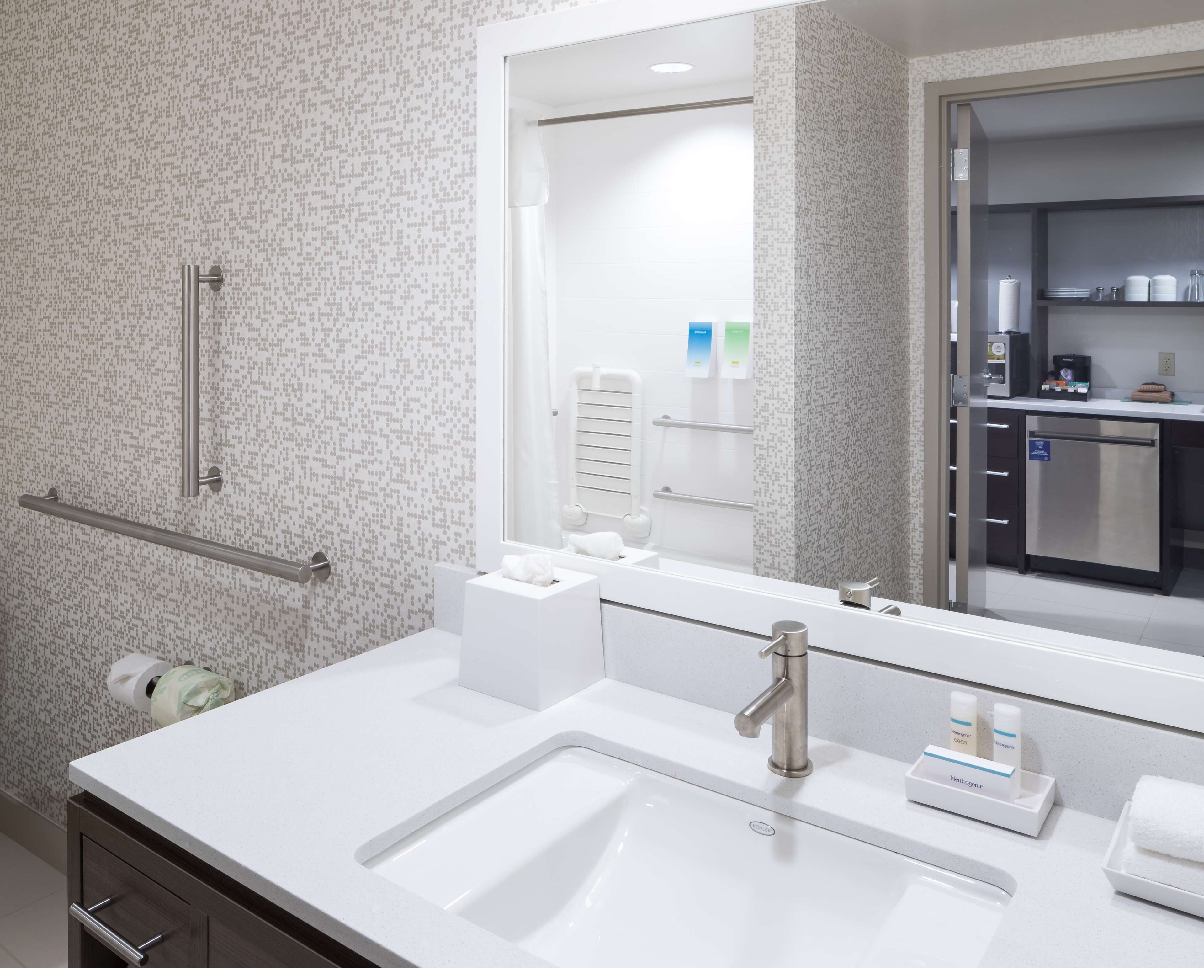 Un baño moderno con lavamanos blanco, un espejo y un perchero para toallas.