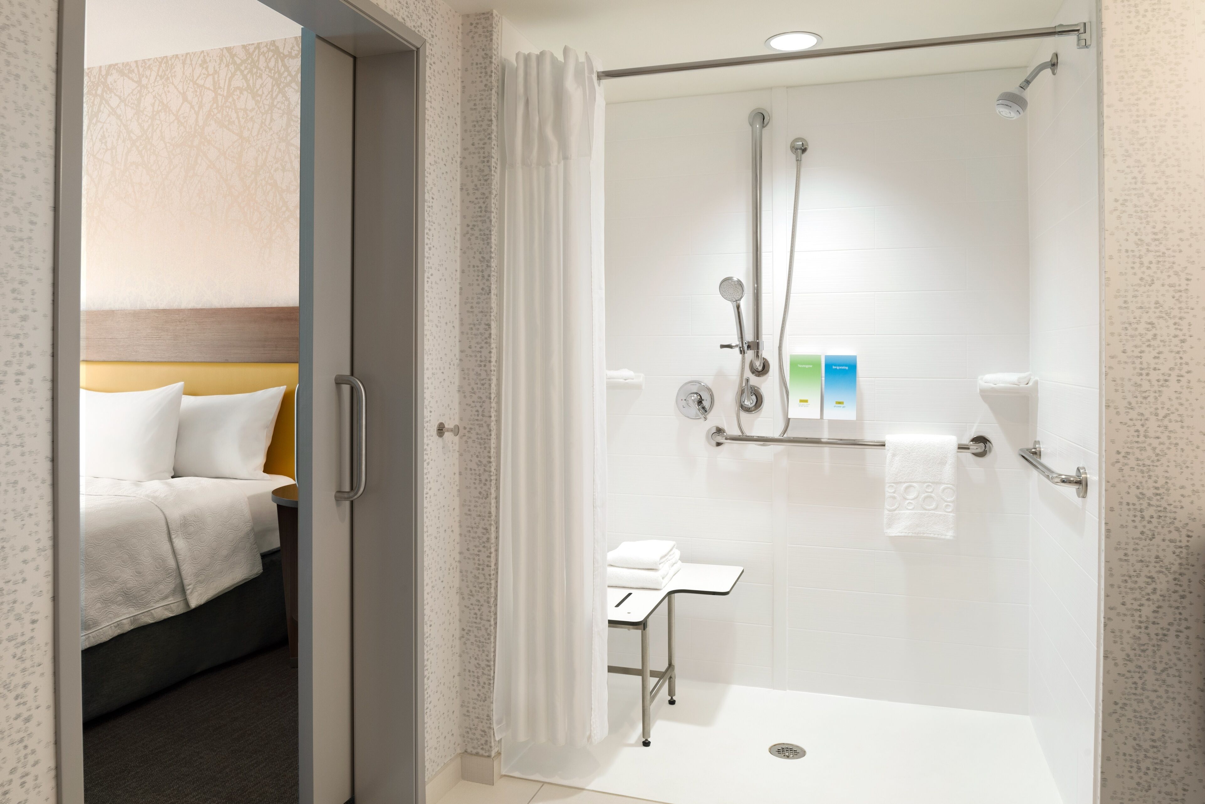 A hotel room with a shower, a bed, and a small table with towels.
