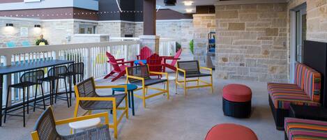 An outdoor patio area with wicker chairs, a red sofa, and a dining table.