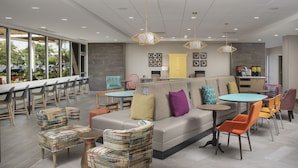 A modern lounge area with a sofa, chairs, tables, and a bar area.