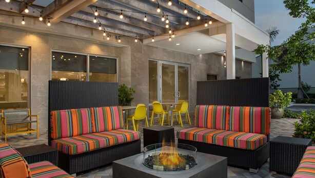 An outdoor seating area with sofas and chairs, a fire pit, and a pergola with string lights.