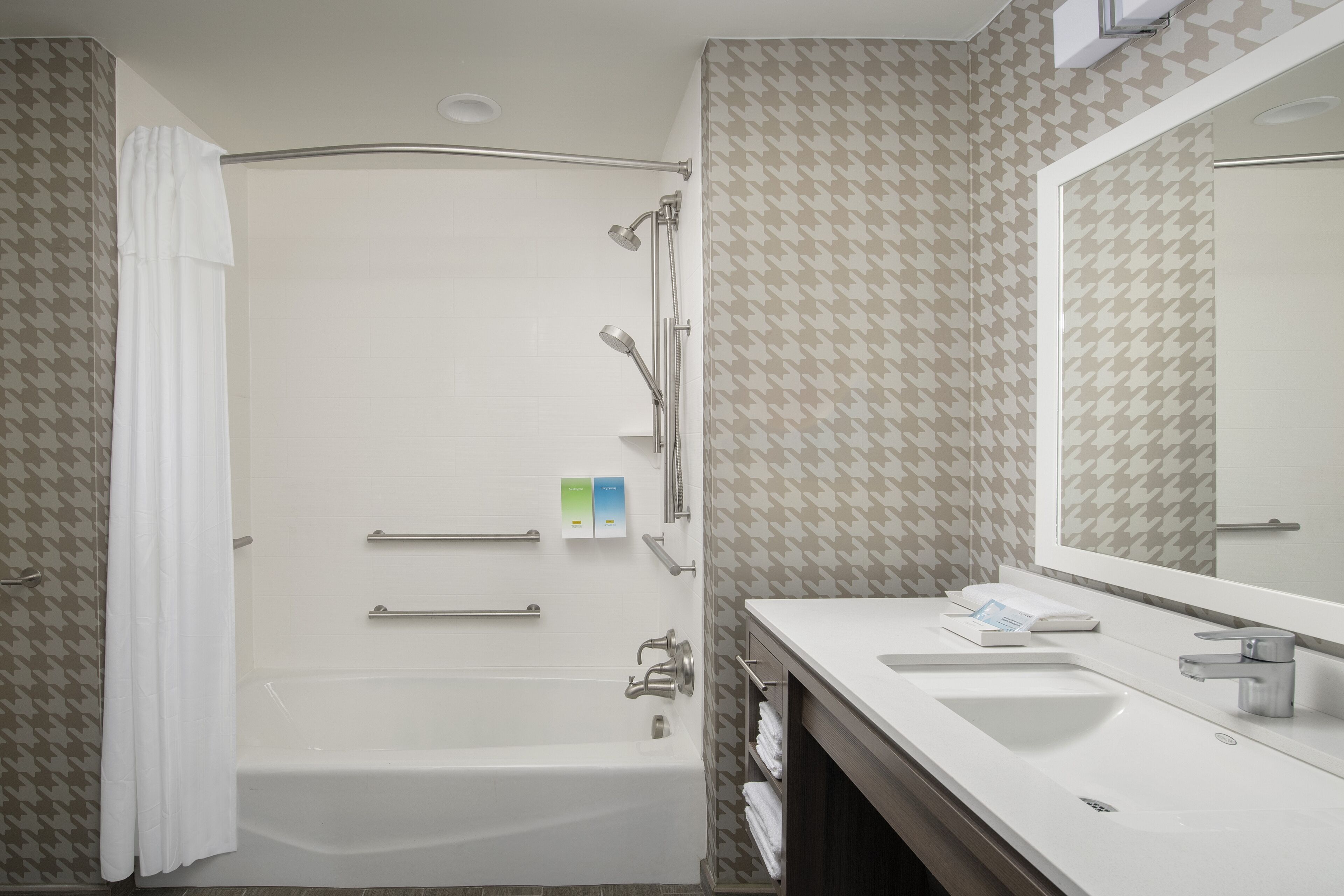 A modern bathroom with a bathtub, a shower, a vanity with a mirror, and a towel rack.