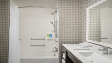 A modern bathroom with a bathtub, a shower, a vanity with a mirror, and a towel rack.