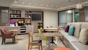 A modern lounge area with seating, a coffee station, and a television.
