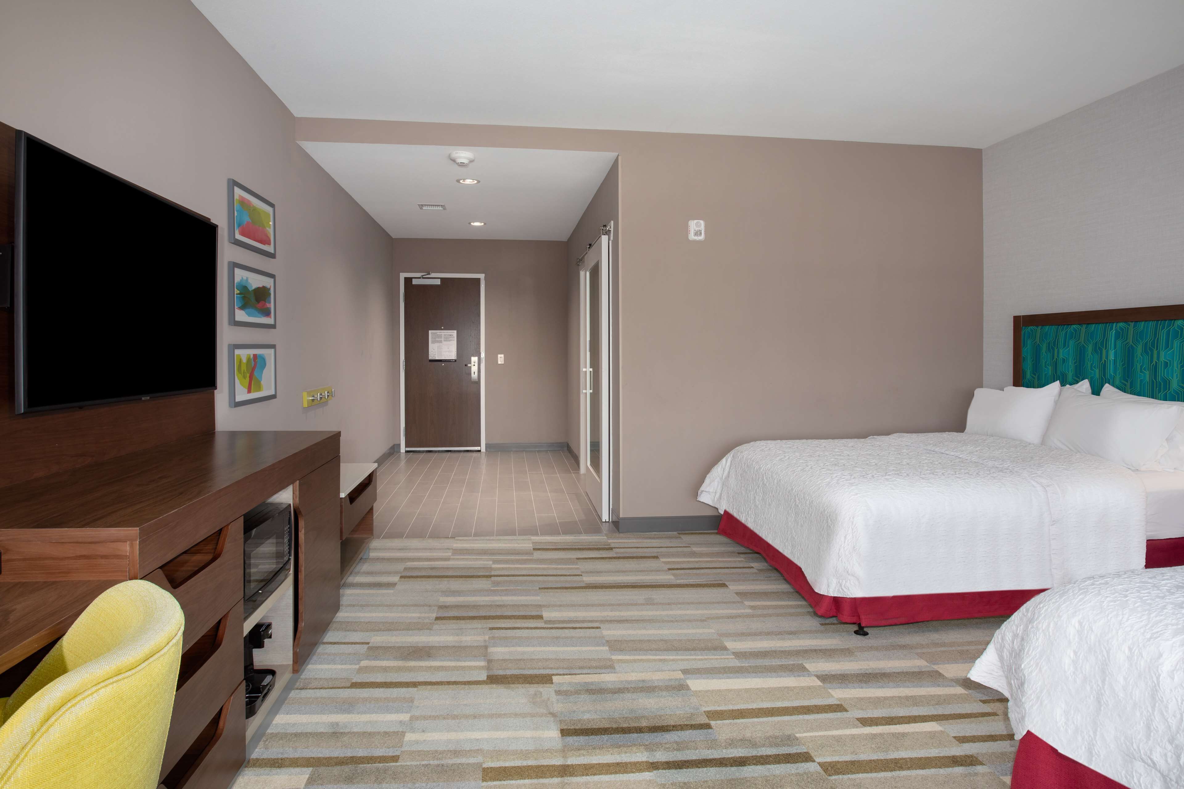 A hotel room with a large bed, a TV, a desk, and a chair.