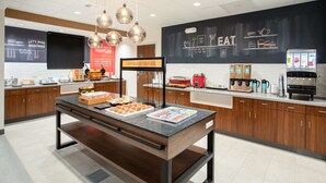 Een moderne keuken met een ontbijtbalk, een pannenkoekenstation en koffieapparaten.
